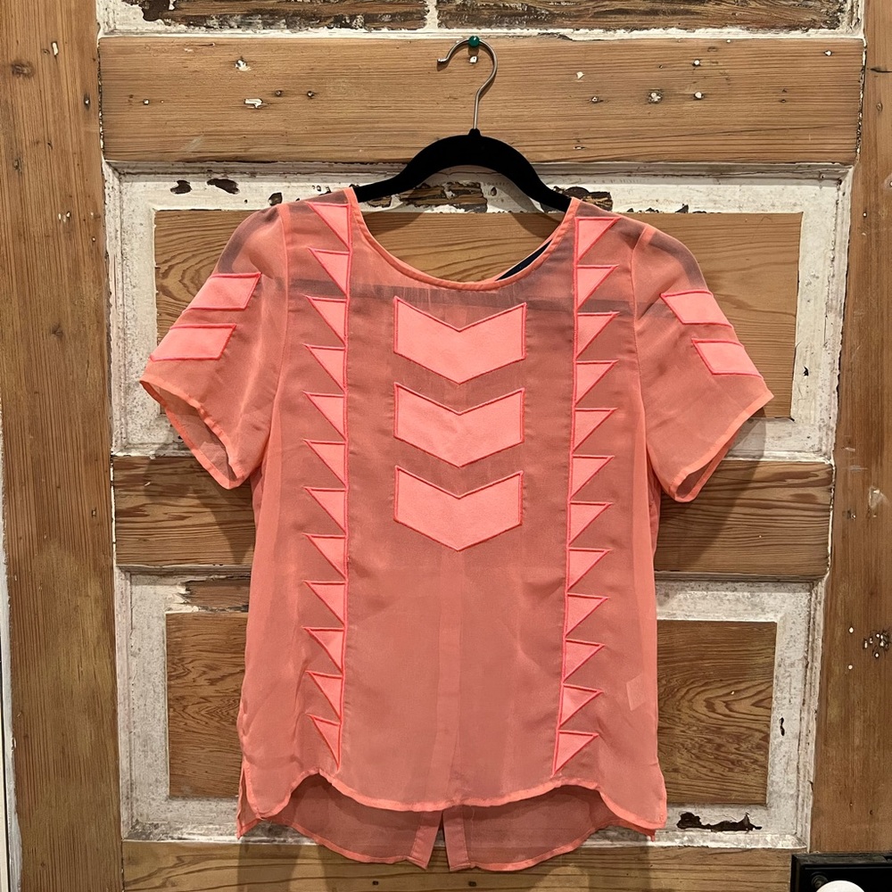 Bright pink sheer blouse with geometric patterning.